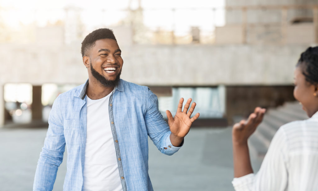 Guy and girl waving at each other in the street